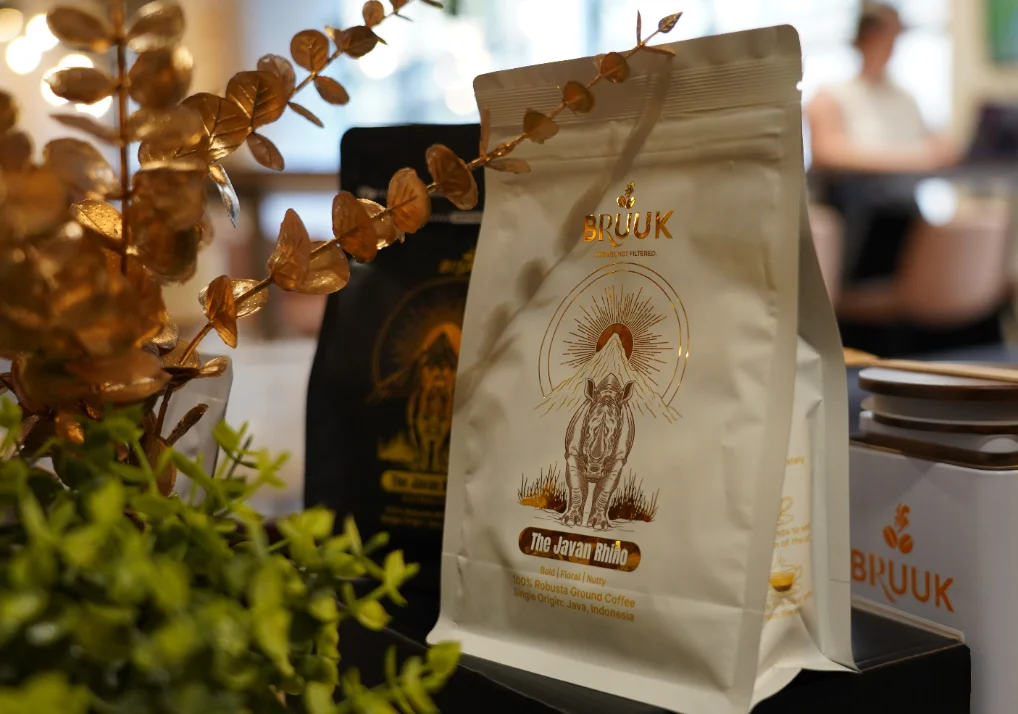 A bag of BRUUK Javan Rhino coffee among gold leaves in a café